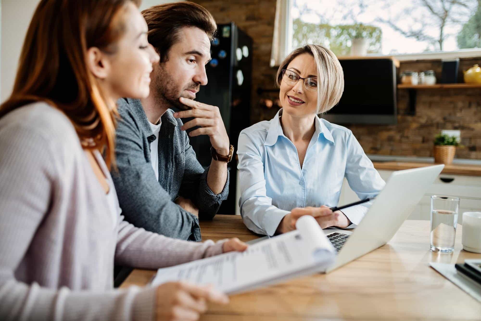 smiling-financial-advisor-using-laptop-while-having-meeting-with-young-couple_637285-5798